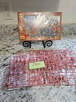 Front of factory-wrapped Strelets box and two red sprues with figures and cannon parts
