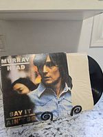 Front cover of Murray Head Say It Ain't So LP on stand with record partially exposed