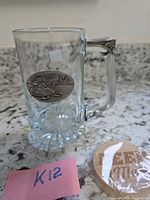 Front view of glass mug showing pewter badge and packaged bottle opener
