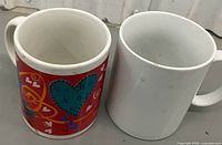 Side view showing both mugs; design details visible