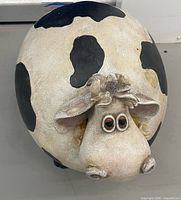 Top view of rounded cow figurine showing flower accent and facial details