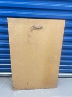 Back of plaque showing particleboard and hanging wire