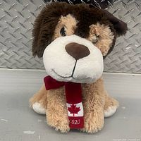 Front view of plush dog showing face, scarf with maple leaf and 2020