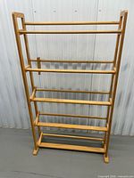 Front view of wooden DVD shelf showing five shelves and top rails