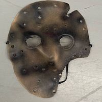 Front view of burn-distressed plastic mask with vent holes