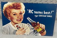 Front view of RC Cola metal sign with Lucille Ball, text and bottle