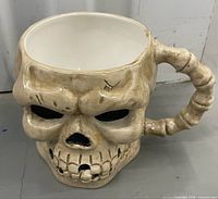 Frontal view of skull mug showing sculpted details and handle