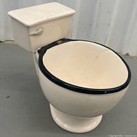 Oblique view of toilet-shaped ceramic mug showing tank, bowl and black rim