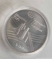 Reverse of 1976 $5 Olympic Village coin in capsule