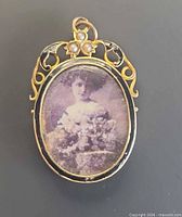 Front view of oval gold locket showing photograph, enamel, seed pearls