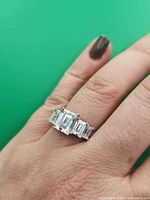 Ring on hand showing five emerald-cut stones in silver-tone setting