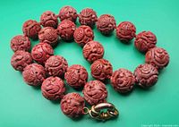 Necklace coiled showing carved cinnabar beads and clasp