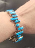 Bracelet worn on wrist showing turquoise stones in sterling silver links