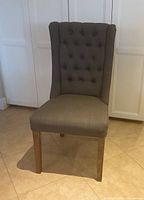Front view of gray tufted dining chair showing upholstery, seat and legs