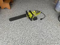 Ryobi chainsaw lying on floor showing full length with scabbard