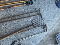 Full view of five long-handled tools lying on floor