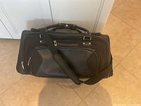 Full view of black Nike duffel bag showing shoulder strap, handles, and exterior pocket