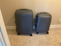 Large and medium grey suitcases standing upright on swivel wheels