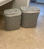 Both grey woven hampers closed, showing size comparison and external condition