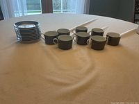 Stack of saucers beside row of cups on table