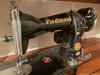 Left front view of Piedmont sewing machine head showing logo, decals, Hudson’s Bay Company badge and needle area