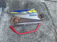 Three saws laid out: Irwin hand saw with sheath, wood-handled hand saw, red bow saw