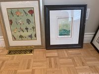 Front view of both framed prints leaning against wall