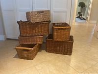 Stack of five wicker baskets in varying sizes plus one seagrass basket nearby