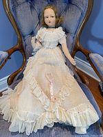 Full view of vintage Farnell Alpha Toy cloth doll seated on chair wearing original dress