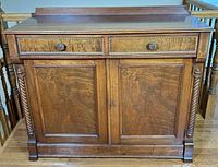 Front view showing drawers, doors, carved columns