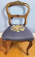 Front view showing balloon back, carved crest, blue floral needlepoint seat