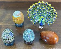 Group view of four eggs on stands and peacock figurine