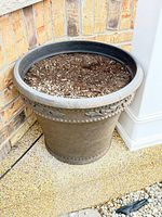 Front view of one planter showing faux stone finish, bead and leaf relief, soil inside