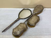 Hand mirror with two matching brushes, silver backs visible