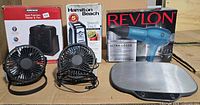 Group shot showing all items including Konwin heater fan box, Hamilton Beach can opener box, Revlon hair dryer box, two desk fans, digital scale
