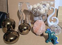Group shot of all decorative items in lot: three gold vases, two acrylic candle holders, glass bowl with spheres, Himalayan salt rock, white swirl sculpture, unicorn figurine, resin paperweight