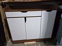 Front view of wood shoe cabinet showing white doors and brown frame