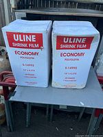 Front view of both sealed Uline Economy Shrink Film cartons showing model, size, gauge