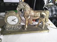 Front view showing horse figure and ornate clock on shared base