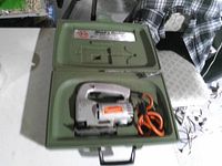 Jigsaw with cord seated inside green plastic case