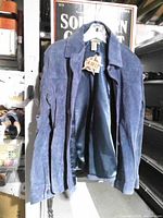 Front view of jacket on hanger displaying color, suede texture, collar, buttons