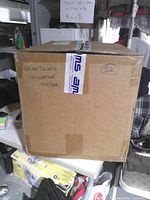 Sealed shipping box labeled 'Shoe Covers Universal 100/pk' with AMS tape