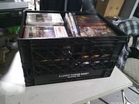 Overall view of black Clover Farms Dairy milk crate filled with DVDs
