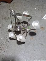 chandelier lying on floor showing six frosted glass shades and brushed nickel frame