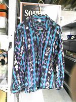 Front view of multicolor long-sleeve button-down shirt hanging, shows pattern, collar, buttons, chest pocket