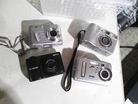 Front view of four digital cameras showing brands and lens areas