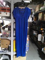 Front view of blue evening gown hanging on rack