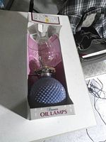 Front view of boxed Kaadan oil lamp showing blue hobnail glass font and branding