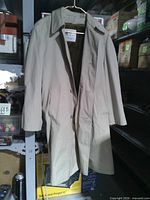 Front view of beige trench coat on hanger