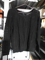 Front view of black mesh long-sleeve Mascara top hanging